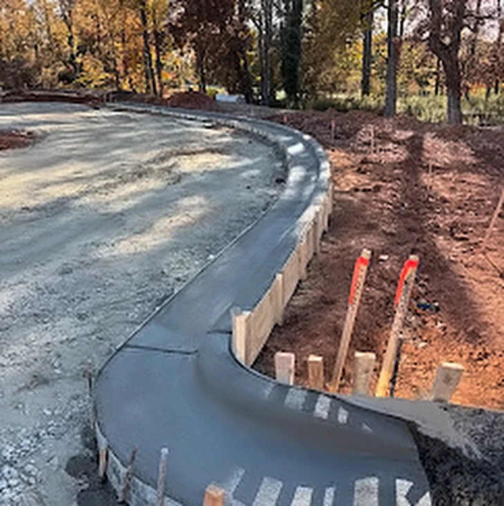A curved concrete curb and gutter poured along a new road