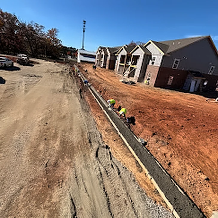 A long concrete curb running beside a new housing development