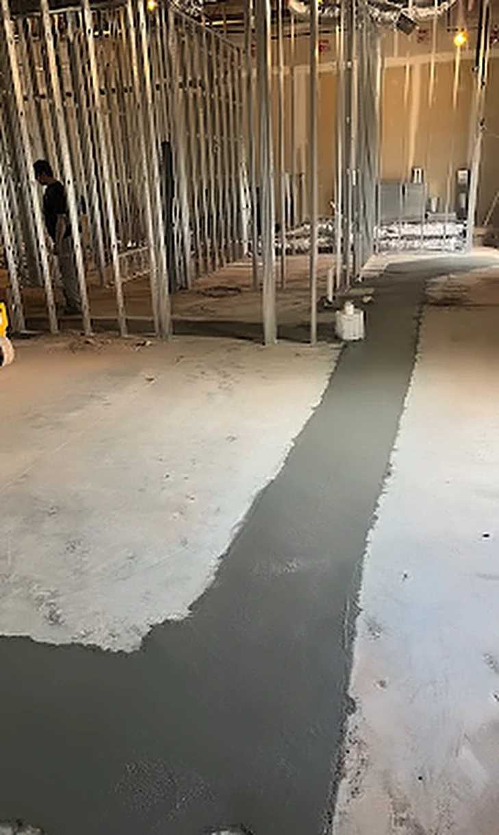 Concrete being placed in an interior footing trench inside a framed building