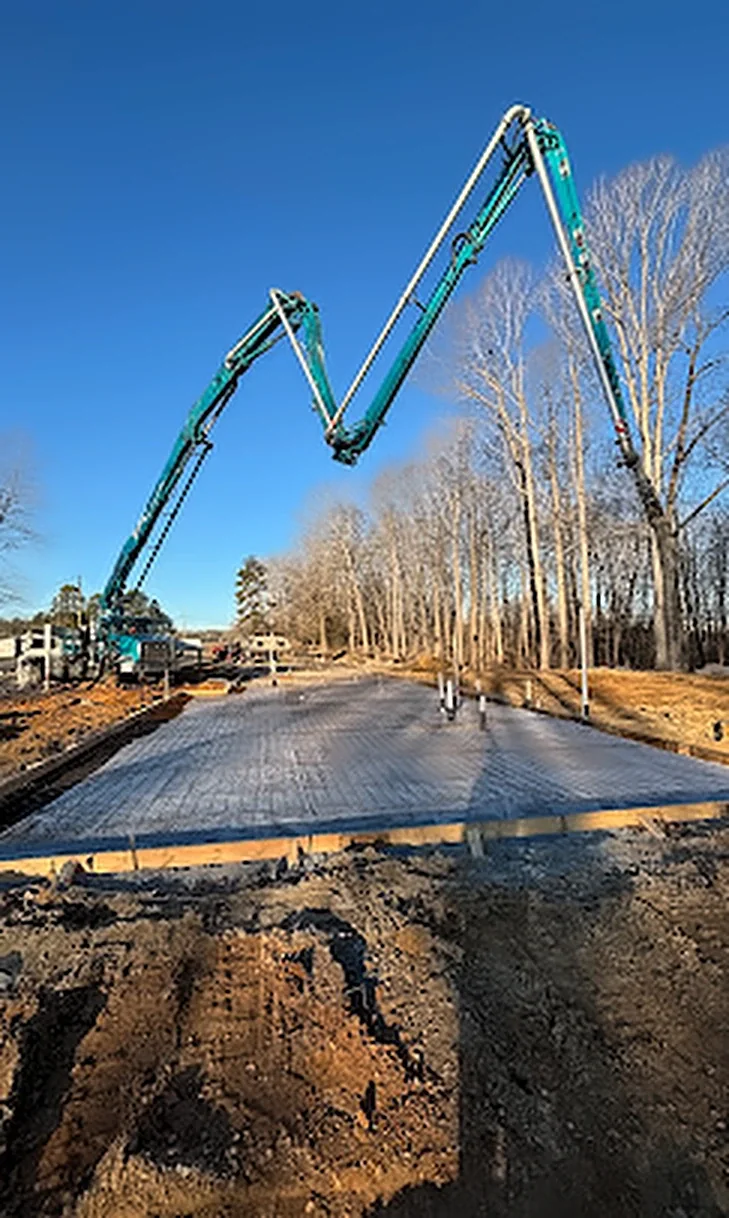 A concrete pump truck boom placing concrete on a house foundation