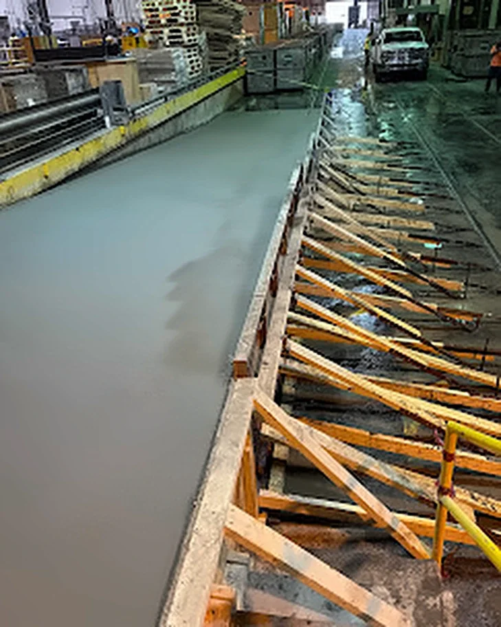 A braced form being filled with concrete along an interior wall of a plant