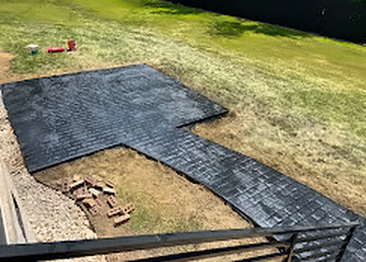 A large finished concrete patio seen from the deck above it