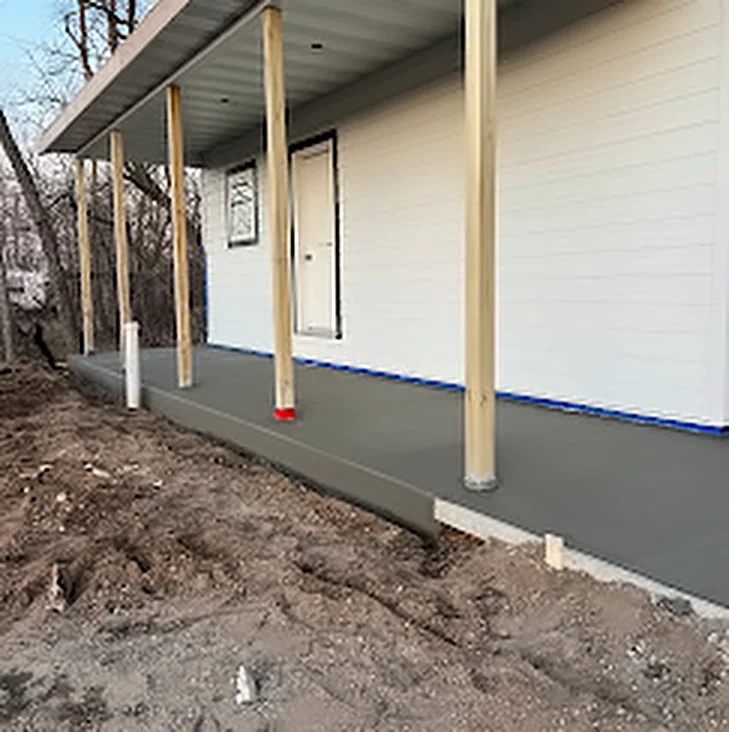 A freshly poured concrete floor under a covered front porch