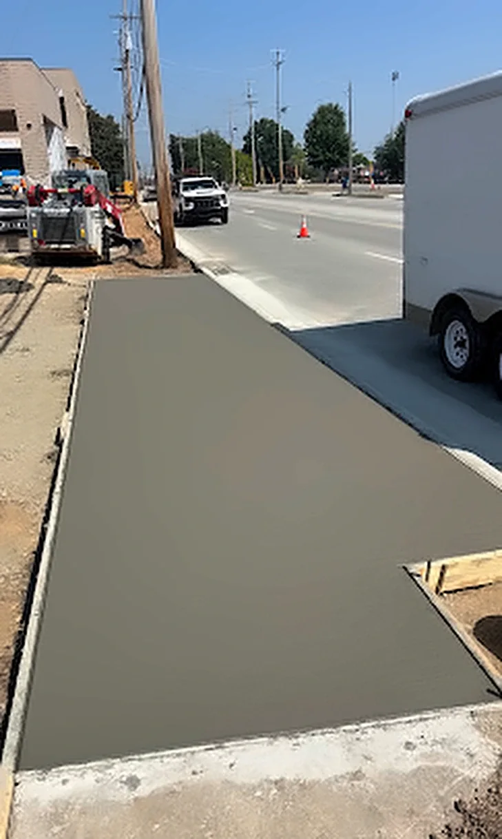 A fresh concrete sidewalk poured along a downtown street