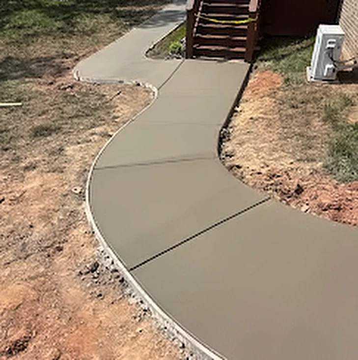 A curved concrete walkway leading to backyard deck steps